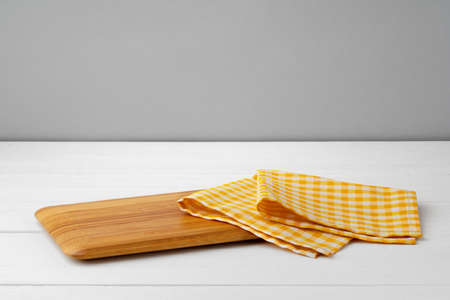 Wooden cutting board on cotton napkin on white wooden table