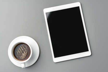 Digital tablet and coffee cup on gray tableの写真素材