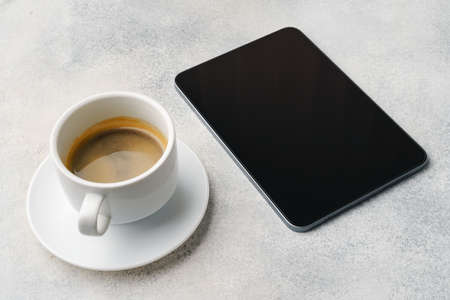 Digital tablet and coffee cup on gray tableの写真素材