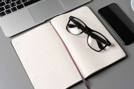 Notepad is on top of office desk table with laptop and suppliesの写真素材