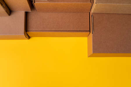 Beige cardboard boxes on yellow background, close up