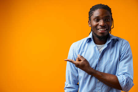Young african american man pointing at copy space over yellow backgroundの写真素材