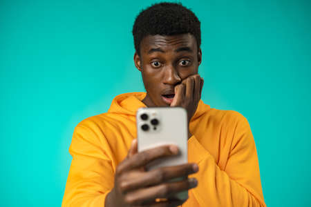 Afro american man using smartphone over isolated mint backgroundの写真素材