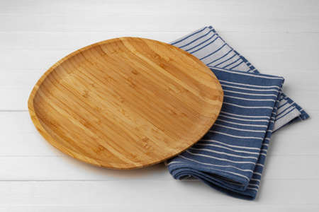 Wooden cutting board on cotton napkin on white wooden tableの写真素材