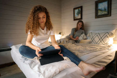 Two beautiful women lying in bed, holding a laptopの写真素材