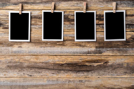 Paper blank photo frames hanging on wooden wall