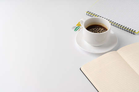Cup of coffee and notepad on white backgroundの写真素材