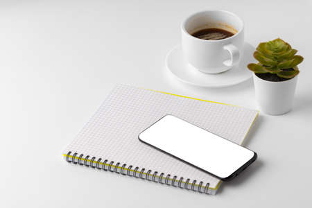 Creative white table with blank cellphone and supplies