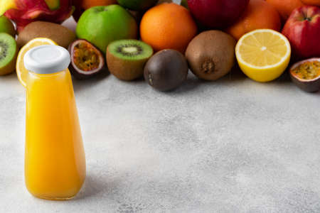 Various fruits and freshly squeezed fruits juice in bottle on gray backgroundの写真素材