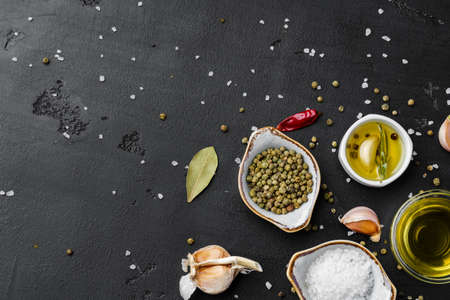 Olive oil, herbs and spices on black background