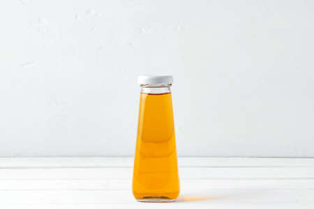 Small glass bottle of fresh juice on white background