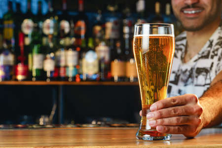 Barman serves glass of cold beer at bar counter in pubの写真素材