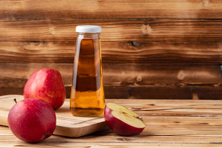 Apple juice in glass bottle with apples on table