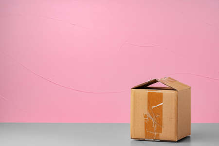 Small carton box against pink background, close up