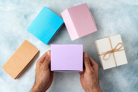 Parcel cardboard box in a man hands on a gray table background