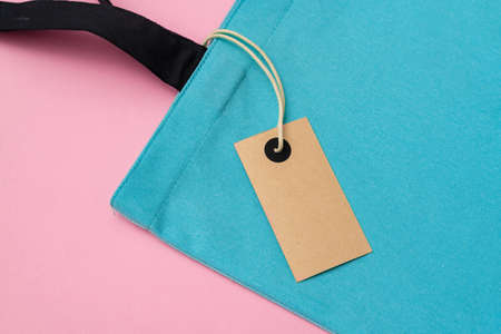 Textile shopping bag on pink paper background flat lay