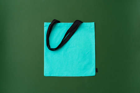 Textile shopping bag on green background flat layの写真素材