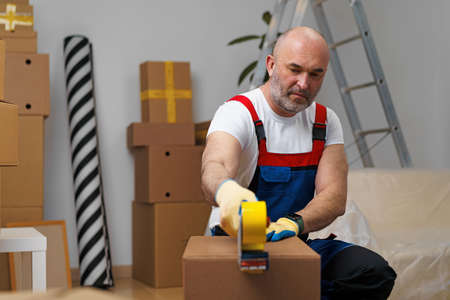 Man mover in uniform packing boxes with tapeの写真素材