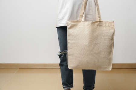 Cropped image of woman holding beige shopping bag in studioの写真素材