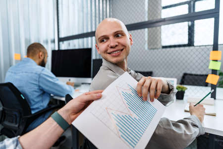 Businessman passing over paper to his colleague in office