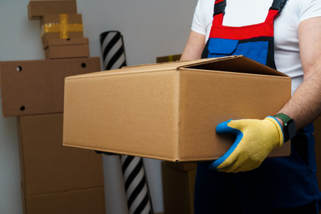 Man mover in uniform holding cardboard box, close up