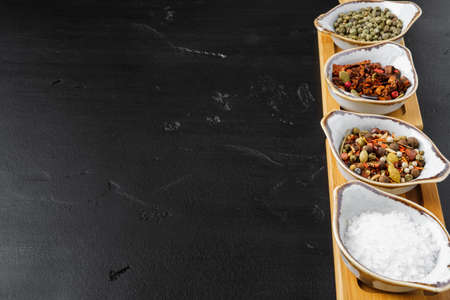 Bowls with spices on black background, copy space