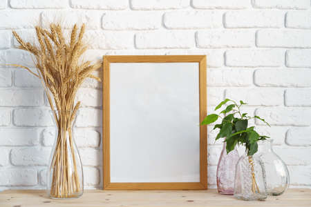 Vase with ears of wheat and photo frames against brick wallの写真素材