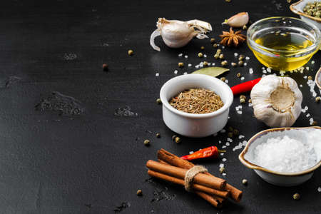 Olive oil, herbs and spices on black background