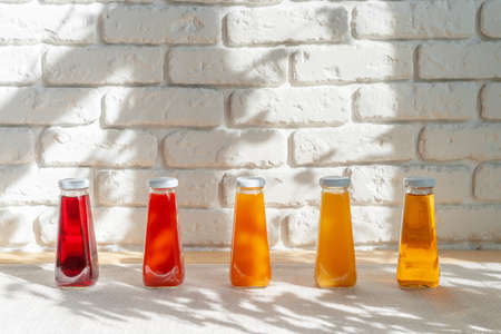 Row of glass bottles of different juices against white brick wallの写真素材