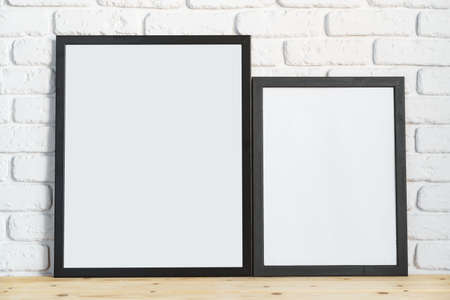 Photo frames on floor over white brick wall