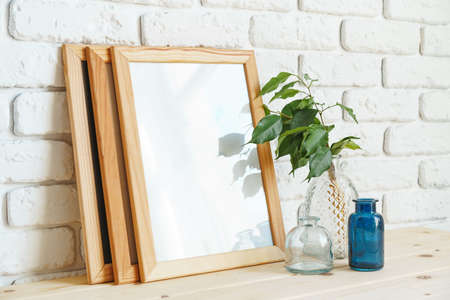 Mockup with a frame and dry flowers in a vase on a white table