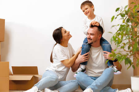 Portrait of happy family with cardboard boxes in new house at moving day