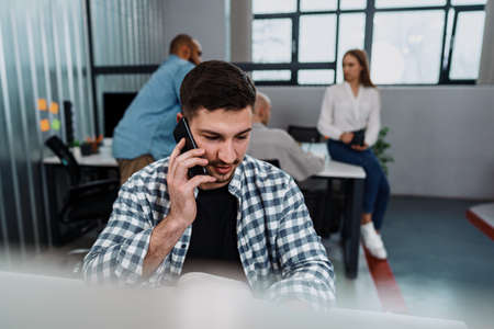 Portrait of young man sitting and working at his desk in the office.の写真素材