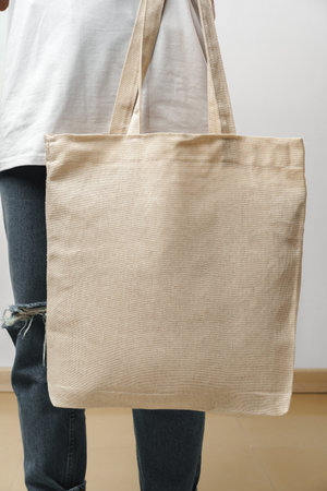 Cropped image of woman holding beige shopping bag in studio