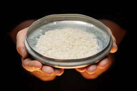 Hands holding a heap of dry rice grain on black backgroundの写真素材