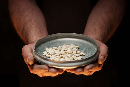 Male hands holding grains of dry kidney beans on dark background