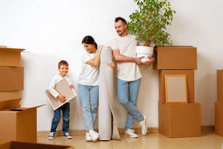 Portrait of happy family with cardboard boxes in new house at moving day