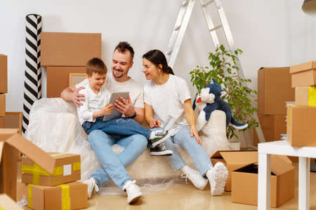 Portrait of happy family with cardboard boxes in new house at moving day