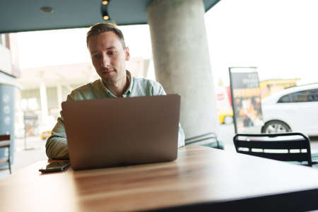 Young businessman sitting in cafe working with laptop computer