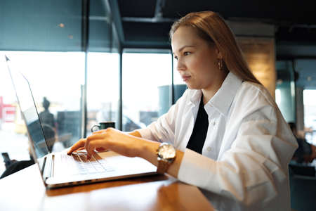 Young businesswoman sitting in a cafe and working with laptop