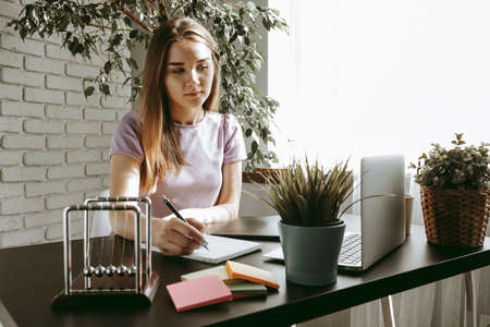 Closeup of young businesswoman working at modern office making notes
