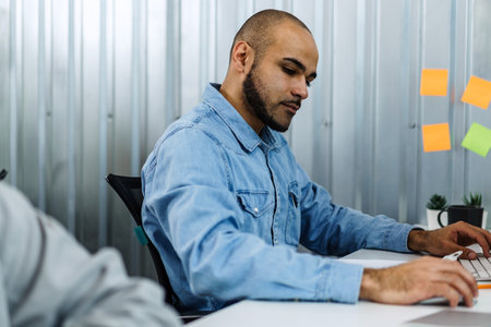 Portrait of young man sitting and working at his desk in the officeの写真素材