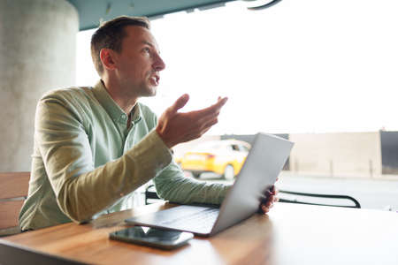 Young businessman sitting in cafe working with laptop computer