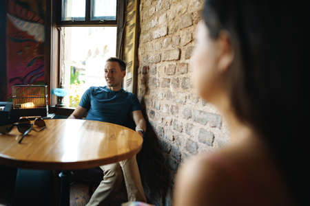 Thoughtful handsome man sitting in cafe and looking awayの写真素材