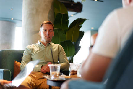 Confident young businessman sitting at street cafeの写真素材