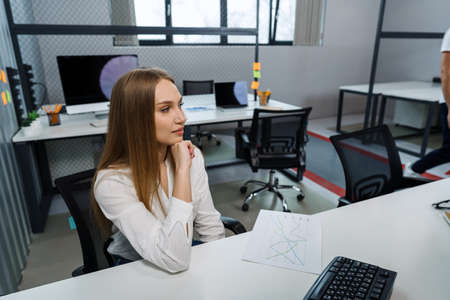 Attractive friendly young businesswoman sitting at the table in office.の写真素材