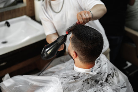 Male client getting haircut by hairdresser in barbershopの写真素材