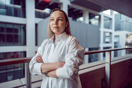 Portrait of young office woman standing on balcony enjoying city view