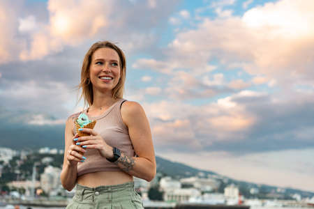 Young woman with ice cream walking in the street