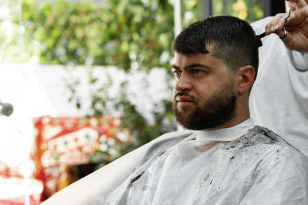 Male client getting haircut by hairdresser in barbershop